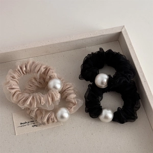 Dettaglio di eleganti elastici in tulle con perle finte in nero e beige