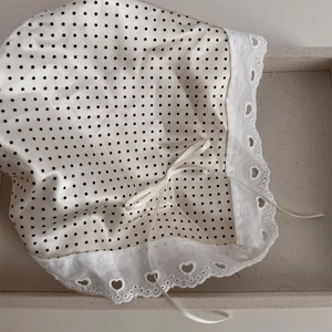 Detail of baby sun hat with black polka dots, white lace edge and heart embroidery