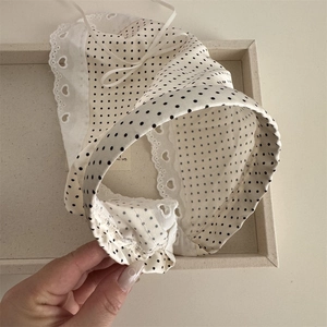 Detailed macro of cream polka dot baby sun hat with delicate heart lace embroidery