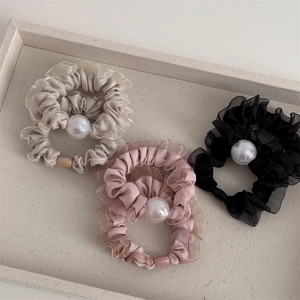 Detailed view of ruffle hair scrunchies with iridescent pearls in black, pink, and grey
