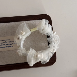 Close-up of white organza scrunchie with embedded pearls on a vintage wooden tray