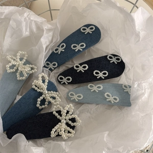 Detailansicht blauer Denim-Haarspangen-Set mit weißen Perlen-Schleifen in einem Metallkorb