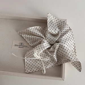 Detailed close-up of cream polka dot lace scrunchie with silky texture and ribbon