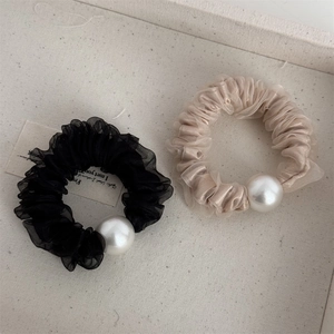 Dettaglio di elastici in mesh nero e champagne con eleganti accenti di perle fini