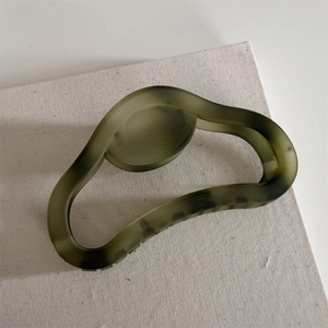 Olive green matte hollow hair claw clip with vintage dark speckle texture on beige canvas