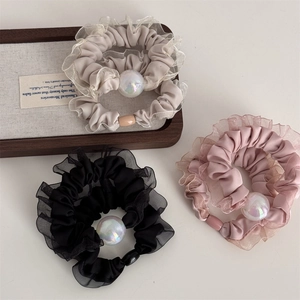 Detailed macro view of satin hair scrunchies with iridescent pearls and mesh lace edges