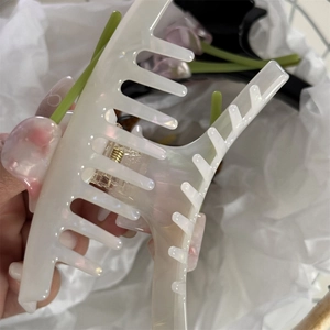 Macro view of Calla Lily acetate hair claw with iridescent finish and gold metal spring