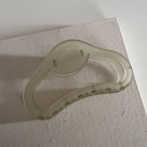 Detail of light green matte frosted hair claw clip on white textured background