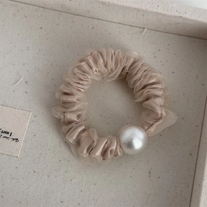 Dettaglio di un elegante elastico in organza beige con decorazione a perla grande