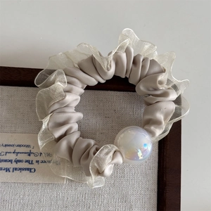 Close-up of cream satin scrunchie with lace edge and iridescent pearl detail