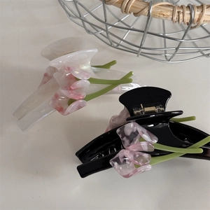 Close-up of acetic acid hair clips featuring 3D pink tulip floral designs in black and white