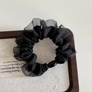 Detailed view of black organza scrunchie with pleated mesh edges and decorative pearl bead