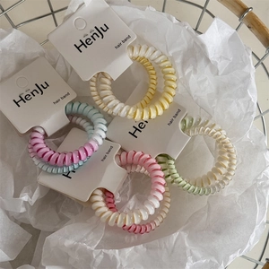 Dettaglio degli elastici a spirale dai colori sfumati in un cesto di metallo decorato