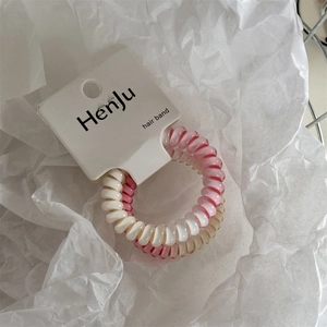Dettaglio degli elastici a spirale rosa sfumato e beige su cartoncino di marca