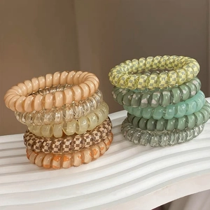 Set of 8 colorful spiral hair ties in solid colors and checkered prints on a white stand