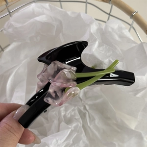 Detail of a large black acetate hair claw featuring pink resin tulip floral ornaments