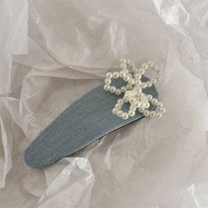 Detail einer hellblauen Denim-Haarklammer mit einer weißen Perlenblume