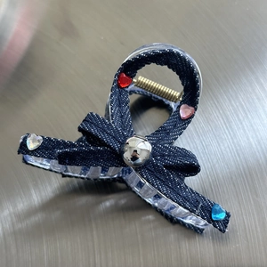 Detail of blue denim bow hair claw with colorful heart rhinestones and silver metal ball