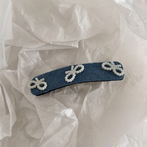Detail der blauen Jeans-Haarklammer mit weißen Kunstperlen-Schleifen auf weißem Papier