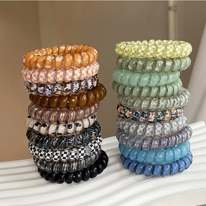 Set of colorful spiral hair ties with checkerboard and floral patterns on a white stand