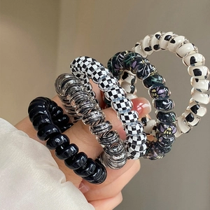Detail of five colorful spiral hair ties including checkerboard and heart patterns