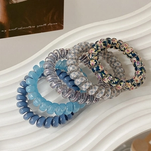 Detailed macro view of four colorful telephone wire hair ties on a white display tray