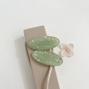 Lot de deux barrettes ovales vert clair translucides avec feuilles d'or sur fond blanc