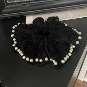 Detail of black lace scrunchie with floral embroidery and white faux pearl trim