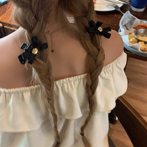 Dettaglio di fermagli per capelli a fiocco nero con bottone dorato sulla modella