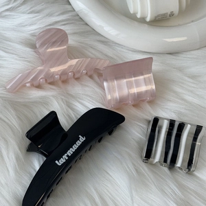 Detail showing pink pearlescent and black acetate hair claw clips on white faux fur