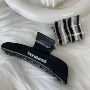 Elegant black and striped acetate hair claw clip set on a soft white faux fur background