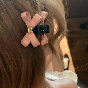 Molla per capelli con fiocco rosa e dettaglio metallico dorato indossata sui capelli