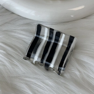 Detailed view of square acetate hair claw clip with black and white vertical stripes