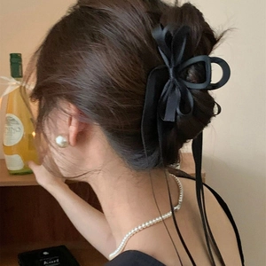 Elegant black fabric bow hair claw clip with long ribbons in a French-style updo