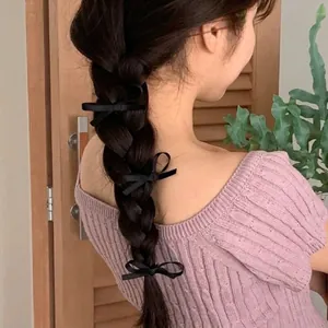 Three pieces of elegant black satin bow hair clips styled on long braided hair