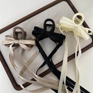 Detail view of fabric bow hair claws in black, beige, and brown with long satin ribbons