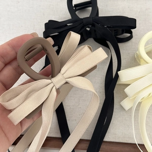 Detail of satin bow claw clips with long ribbons in black, beige and cream colors