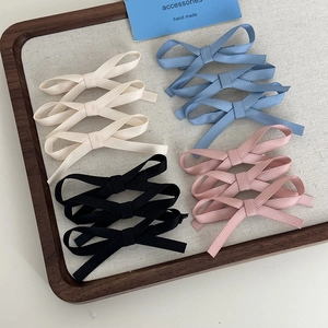 Close-up of four colors of ribbon bow hair clips on a textured wooden display board
