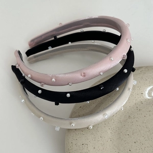 Close-up of satin padded headbands with pearls and crystals in pink, black, and beige colors