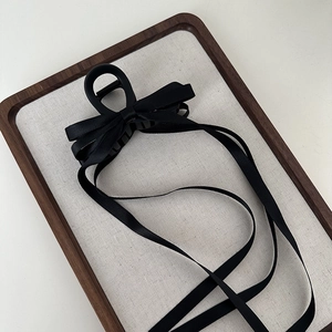 Detailed shot of an elegant black fabric bow hair claw clip with long ribbon streamers