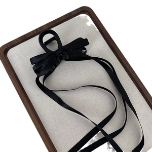 Elegant black ribbon bow hair claw clip with long streamers on a luxury display tray