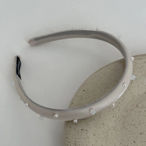 Detail of champagne satin headband with white pearls, crystals, and handmade label tag