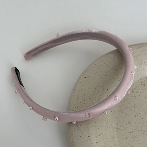 Detail of pink satin headband with white pearls and square crystals on ceramic tray