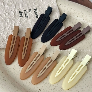Close-up of ten matte duckbill hair clips in Morandi earth tones on a ceramic tray