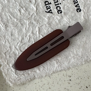 Close-up of matte coffee and metallic grey non-marking hair clip on vintage paper background