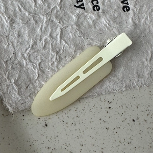 Macro view of cream matte hair clip on textured ceramic and handmade paper background
