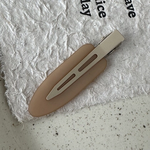 Detailed close-up of earth-toned matte resin hair clip with silver metal duckbill base