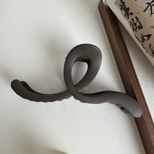 Macro shot of large wave matte brown claw clip showing elegant twisted cross structure