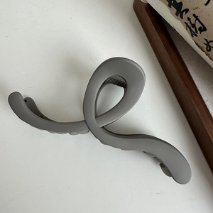 Close-up of minimalist dark gray matte shark hair clip with a stylish twisted structure