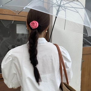 Elegant pink satin rose hair scrunchie shown on a braided hairstyle with soft lighting